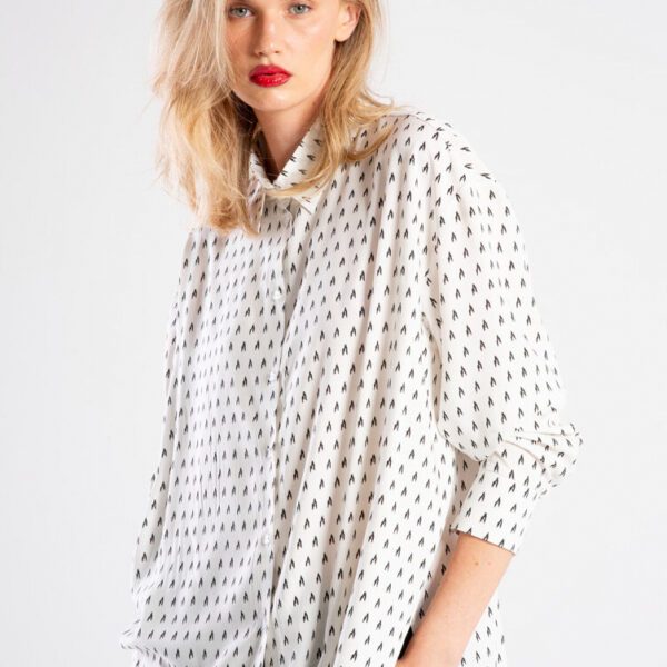 Modelka w koszuli Niigata White od delCane, ujęcie od tyłu, widoczna cała sylwetka. Koszula z włoskiej wiskozy w drobny czarny wzór, o luźnym kroju oversize i zaokrąglonym, lekko dłuższym tyle.