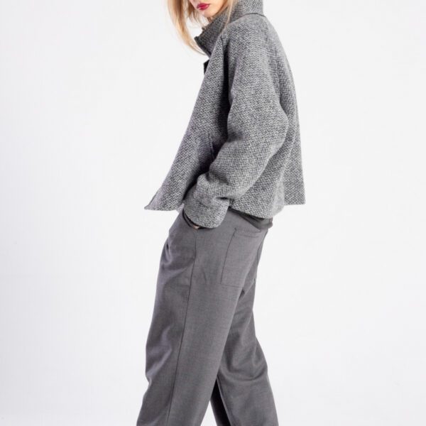 Modelka w kurtce Niigata Grey od delCane, ujęcie z boku, twarz skierowana do przodu, ręce w kieszeniach spodni.