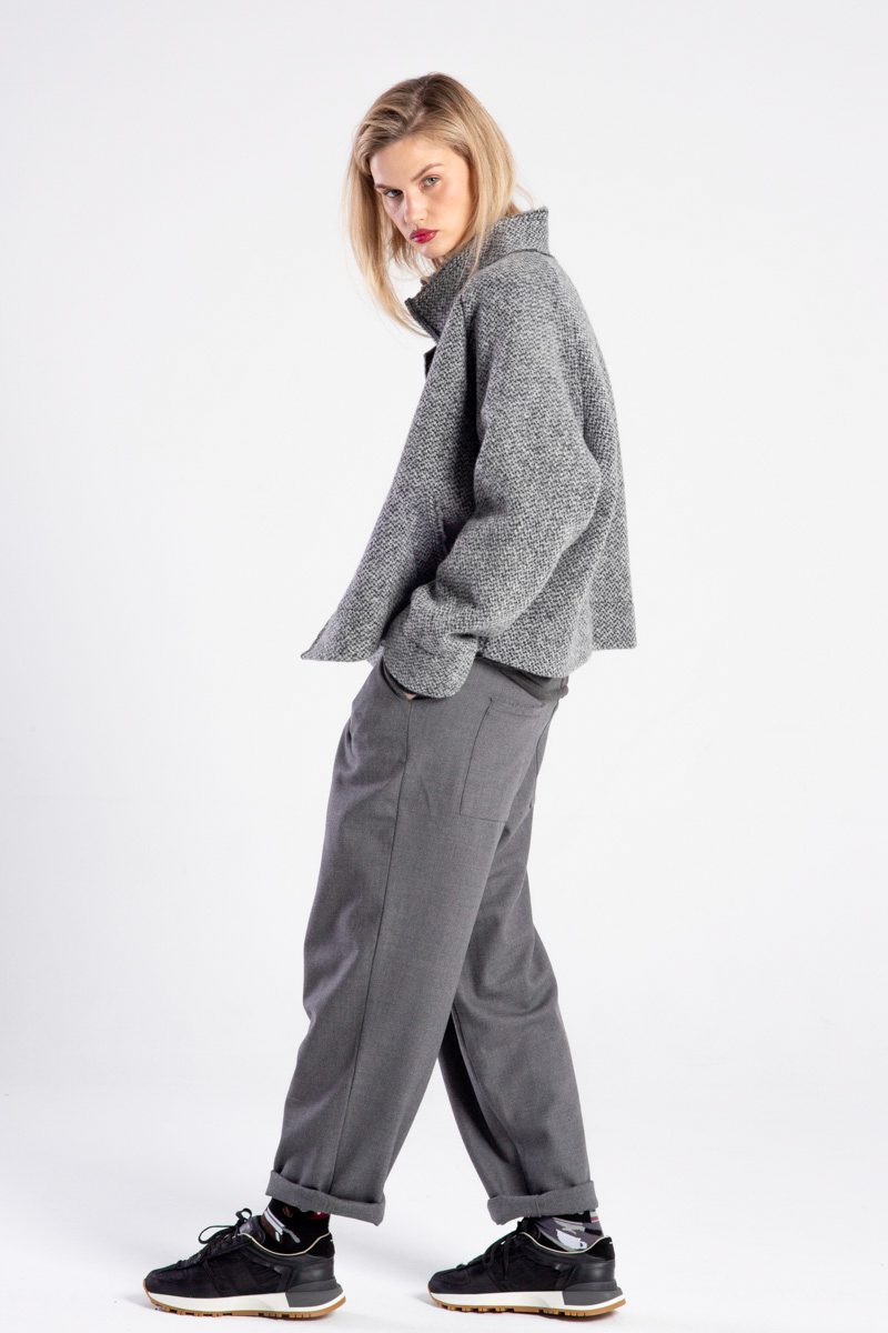Modelka w kurtce Niigata Grey od delCane, ujęcie z boku, twarz skierowana do przodu, ręce w kieszeniach spodni.