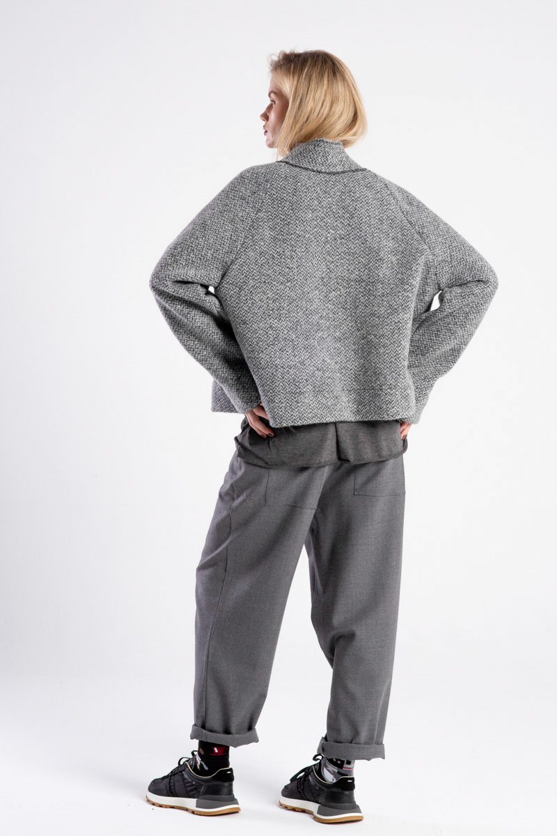 Modelka w kurtce Niigata Grey od delCane, widok z tyłu z lekko widocznym profilem, ręce na biodrach.