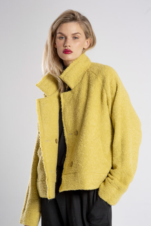 modelka w kurtce Niigata Yellow z wełny boucle, ujęcie przodem z lekkim bokiem, zbliżenie od bioder w górę, rozpięta kurtka