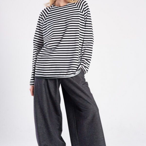Modelka w longsleeve’ie Niigata Stripes od delCane, cała sylwetka przodem, jedna ręka w kieszeni spodni, druga opuszczona.