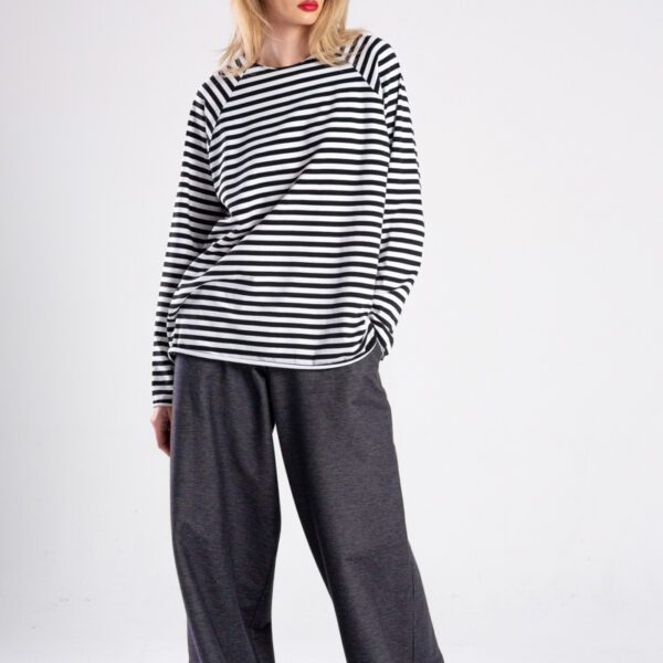 Modelka w longsleeve’ie Niigata Stripes od delCane, cała sylwetka przodem, spojrzenie w bok, ręka w kieszeni.