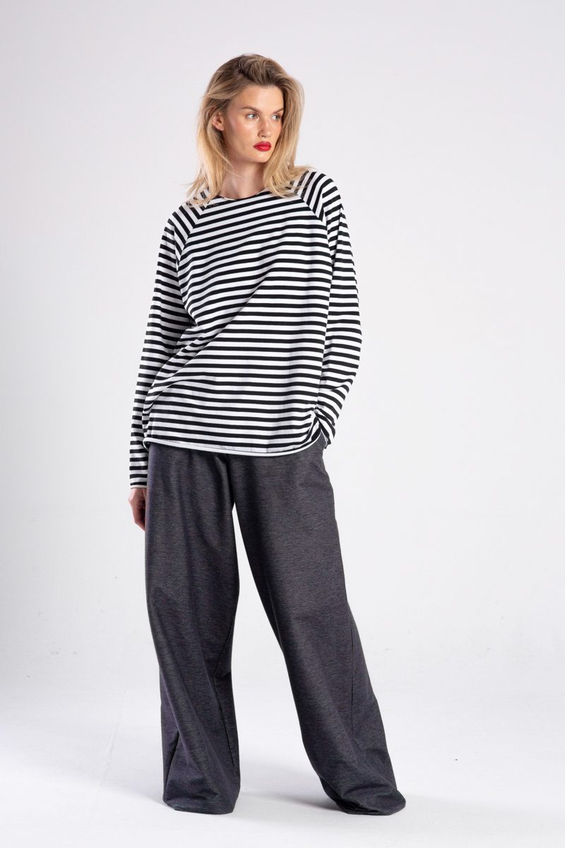 Modelka w longsleeve’ie Niigata Stripes od delCane, cała sylwetka przodem, spojrzenie w bok, ręka w kieszeni.
