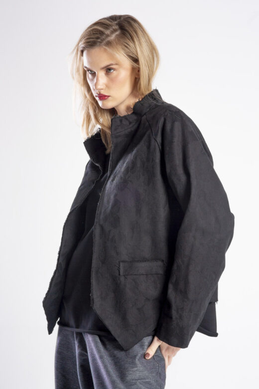 Modelka w marynarce Niigata Noir od delCane, ujęcie z boku w mocnym zbliżeniu, widoczny oversize’owy krój, faktura i wzór żakardowej tkaniny.