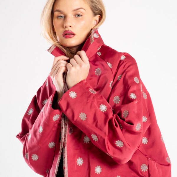 Modelka w marynarce Niigata Red od delCane, ujęcie w mocnym zbliżeniu z lekkiego boku, widoczna struktura żakardowej tkaniny i wzór.