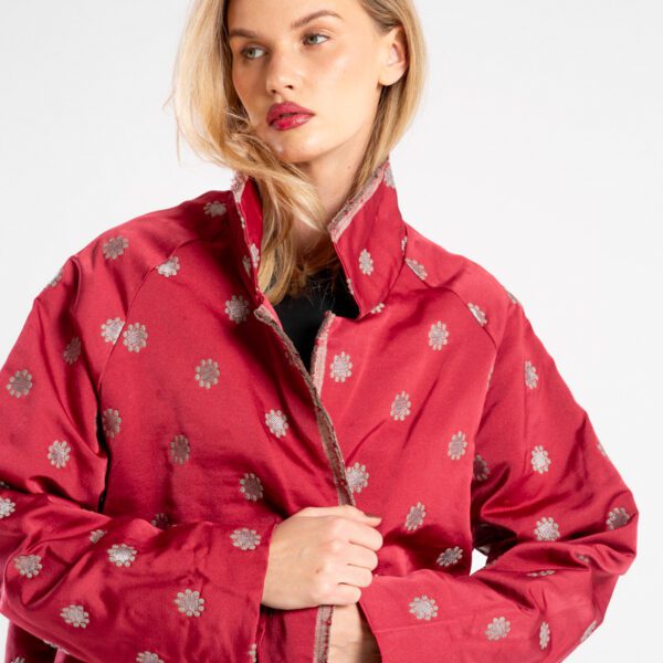 Modelka w marynarce Niigata Red od delCane, ujęcie z przodu w zbliżeniu, ręce trzymają przód marynarki, widoczne wykończenie kołnierza, przodu i struktura tkaniny.