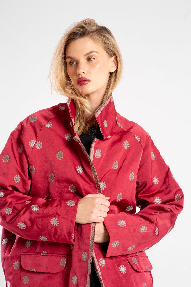 Modelka w marynarce Niigata Red od delCane, ujęcie z przodu w zbliżeniu, ręce trzymają przód marynarki, widoczne wykończenie kołnierza, przodu i struktura tkaniny.