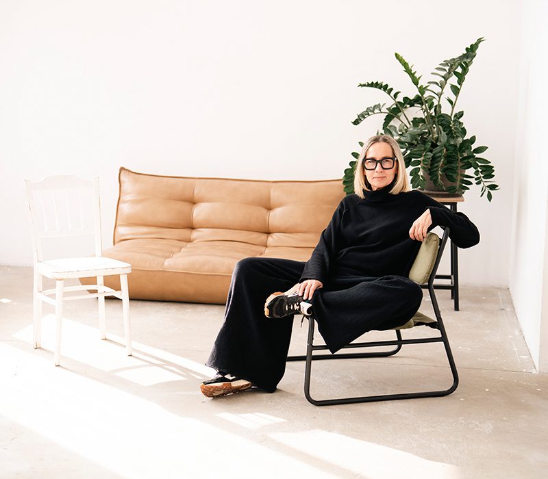 projektantka i założycielka delcane, ewa lignowska, w lifestyle'owej stylizacji w studio, siedząca na fotelu.