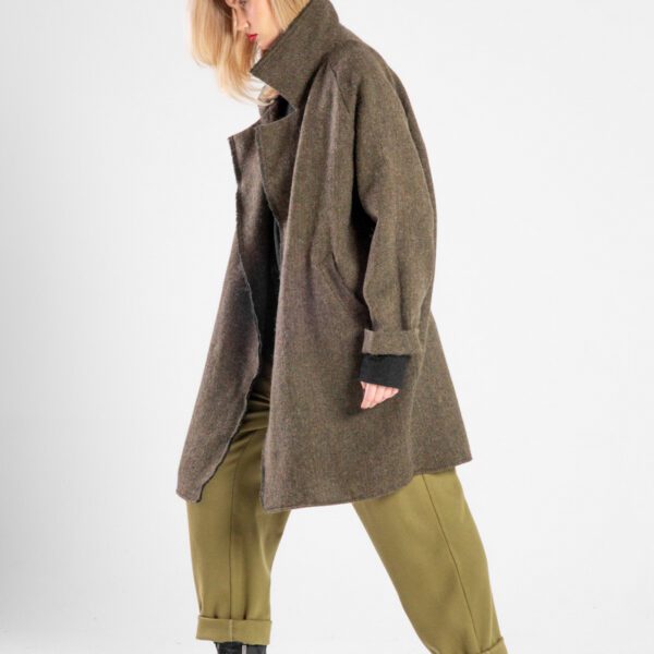 Modelka w płaszczu Niigata Khaki od delCane, ujęcie z boku w ruchu, widoczna cała sylwetka.