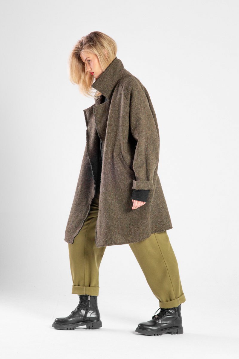 Modelka w płaszczu Niigata Khaki od delCane, ujęcie z boku w ruchu, widoczna cała sylwetka.