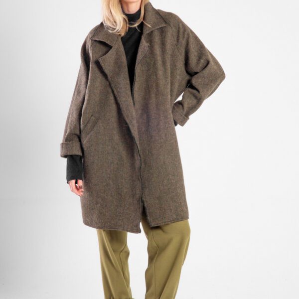 Modelka w płaszczu Niigata Khaki od delCane, widok z przodu, płaszcz rozpięty, luźna poza, widoczna cała sylwetka.
