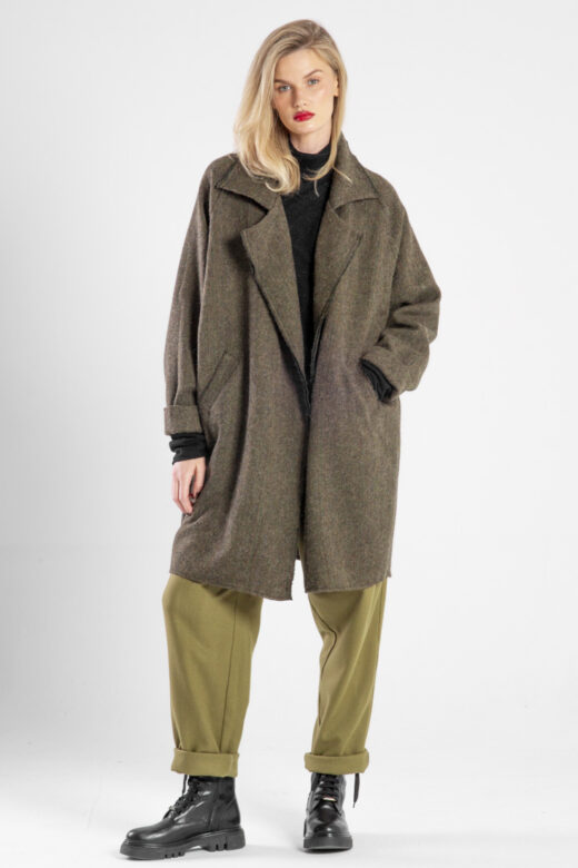 Modelka w płaszczu Niigata Khaki od delCane, widok z przodu, jedna ręka w kieszeni, druga opuszczona, płaszcz luźno.