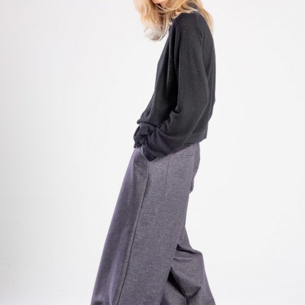 Modelka w spodniach Niigata Jeans od delCane, cała sylwetka z boku — ręka w kieszeni, widoczny bok i szeroka nogawka.
