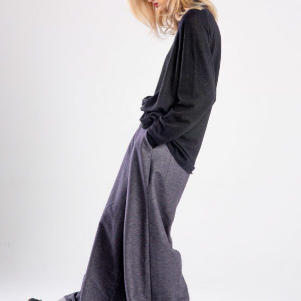 Modelka w spodniach Niigata Jeans od delCane, cała sylwetka z boku — lekko odchylona do tyłu, ręka w kieszeni spodni.