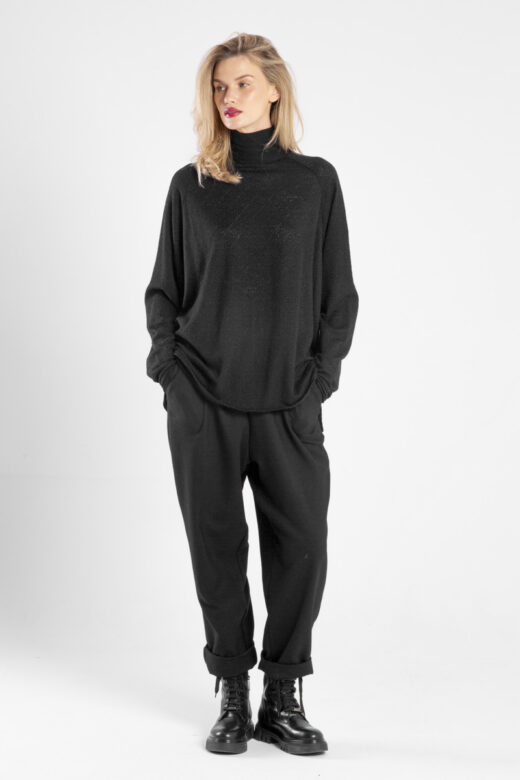 Modelka w czarnym golfie Niigata Cashmere od delCane, widok z przodu z rękami w kieszeniach.