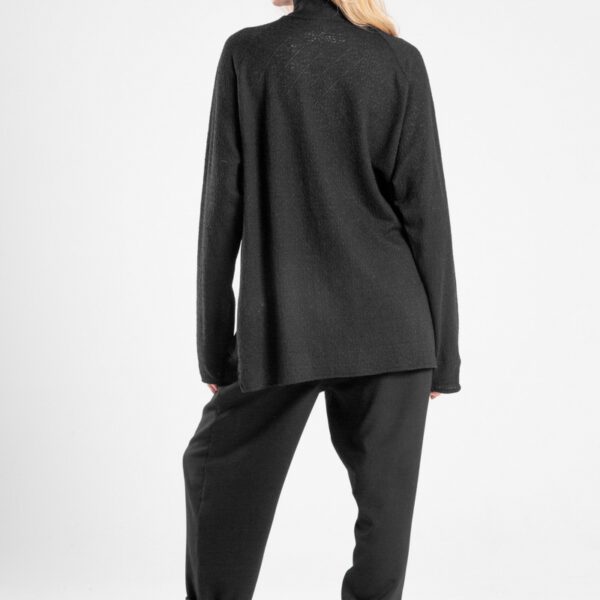 Modelka w czarnym golfie Niigata Cashmere od delCane, ujęcie z tyłu w swobodnej pozie.