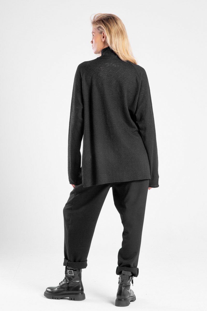 Modelka w czarnym golfie Niigata Cashmere od delCane, ujęcie z tyłu w swobodnej pozie.