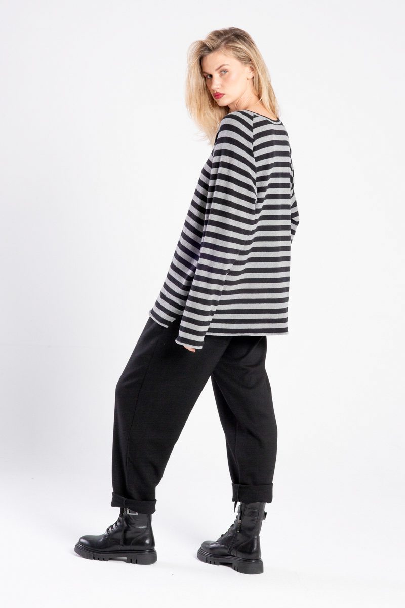 Modelka w swetrze Niigata Stripes od delCane, ujęcie tyłobokiem, cała sylwetka, twarz skierowana do przodu.