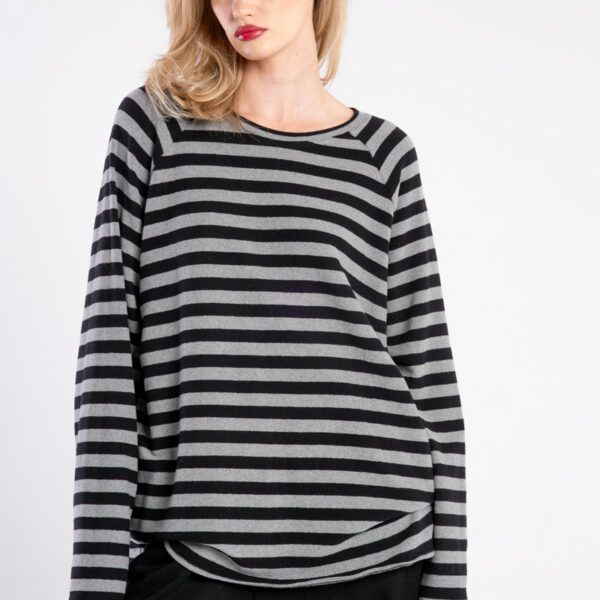 Modelka w swetrze Niigata Stripes od delCane, ujęcie z przodu w zbliżeniu, widoczne detale tkaniny i pasiasty wzór, ręce opuszczone.