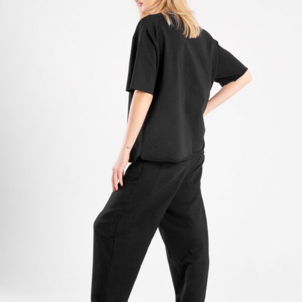 modelka w t-shircie Niigata Black, pełna sylwetka tyłobokiem, profil twarzy, ręka na biodrze, widoczny tył i bok t-shirtu