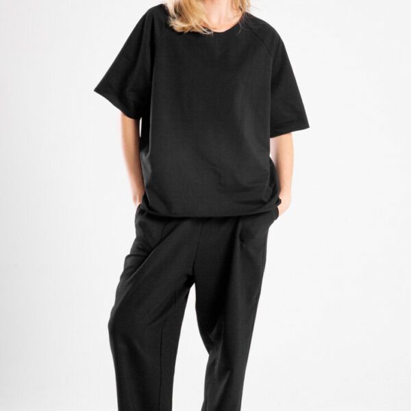 modelka w t-shircie Niigata Black, pełna sylwetka przodem, ręce w kieszeniach spodni, patrzy w obiektyw, widoczny cały t-shirt