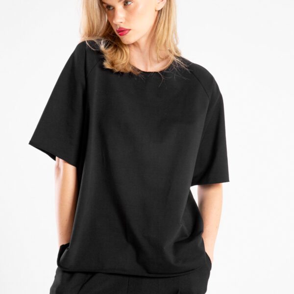 modelka w t-shircie Niigata Black, ujęcie przodem od uda w górę, twarz skierowana w bok, ręce w kieszeniach spodni, zbliżenie na przód t-shirtu