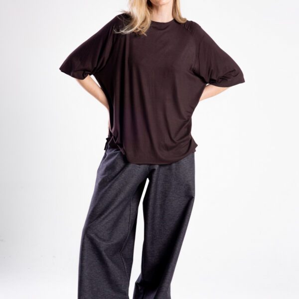 Modelka przodem w brązowym t-shircie oversize, cała sylwetka, ręce oparte z tyłu.