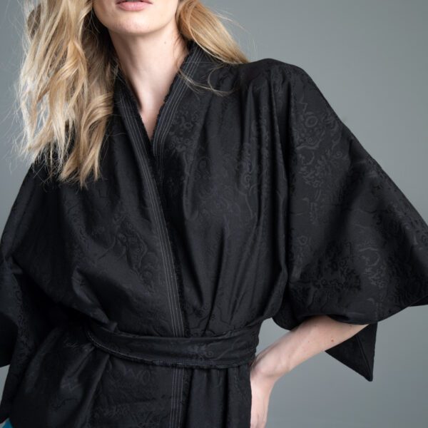 Modelka przodem prezentuje kimono Noda Black w ujęciu od uda w górę, kimono jest związane, wyraźnie widać fakturę i wzór żakardu oraz fragment rękawa.