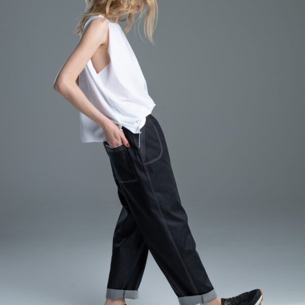 Modelka w spodniach Noda Black, ujęcie z boku, cała sylwetka, ręka w tylnej kieszeni