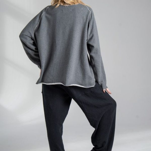 Szara bluza Mino Gray delCane z bawełny. Modelka w pełnej sylwetce, widok od tyłu, z jedną ręką i jedną nogą lekko ugiętą.