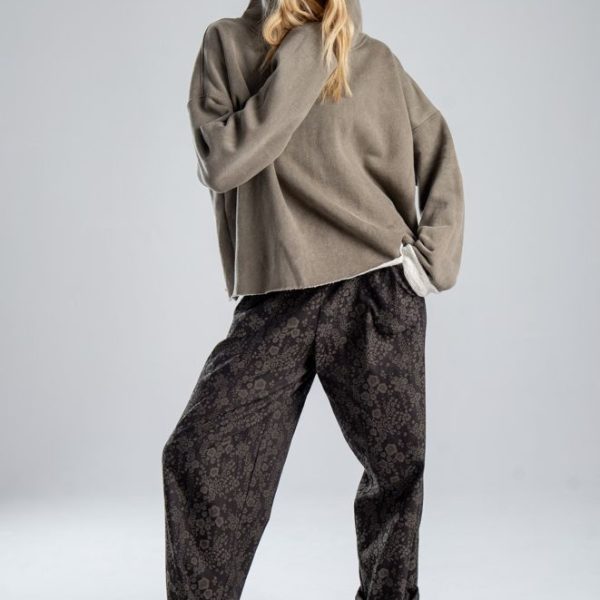 Bluza Mino Stone delCane w szarobeżowym kolorze. Modelka przodem, z kapturem na głowie, jedną ręką przytrzymuje górę bluzy, drugą trzyma w kieszeni spodni.