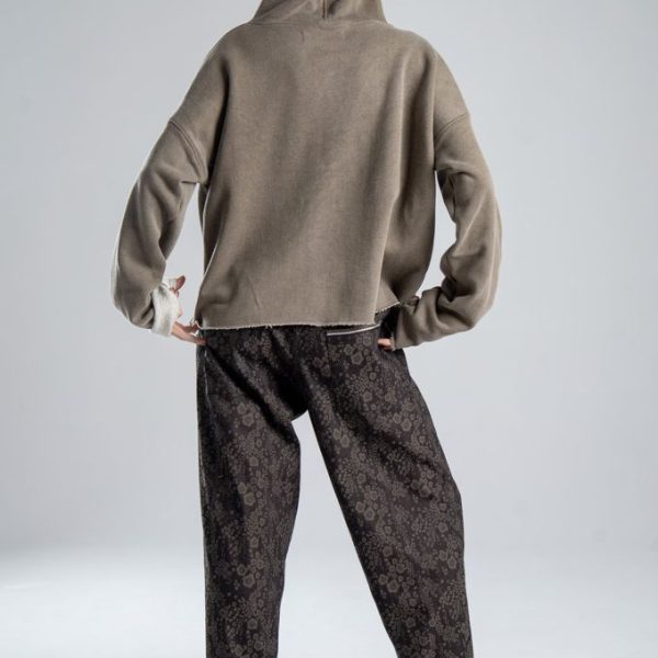 Bluza Mino Stone delCane w szarobeżowym kolorze. Modelka w pełnej sylwetce, widok od tyłu, z kapturem na głowie i dłońmi przy dolnej krawędzi bluzy.