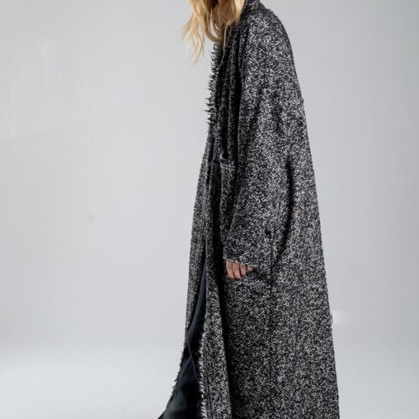 Cardigan Mino Wool delCane w czarno-białym melanżu. Modelka ustawiona bokiem, w pełnej sylwetce, z rękami opuszczonymi wzdłuż ciała, patrzy w obiektyw.