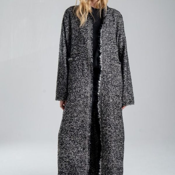 Cardigan Mino Wool delCane w czarno-białym melanżu. Modelka przodem, w pełnej sylwetce, z rękami opuszczonymi wzdłuż ciała. Wyraźnie widoczny przód cardiganu.