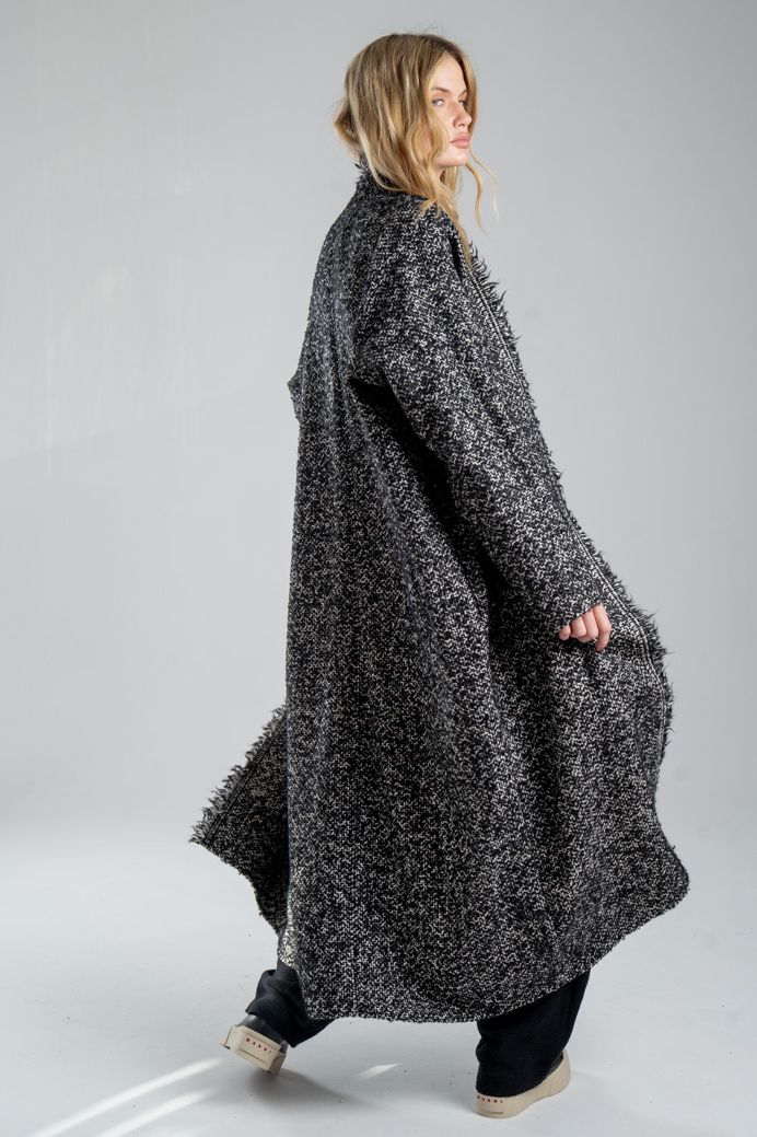 Cardigan Mino Wool delCane w czarno-białym melanżu. Modelka ustawiona tyło-bokiem, w ruchu. Widoczny bok i tył cardiganu.