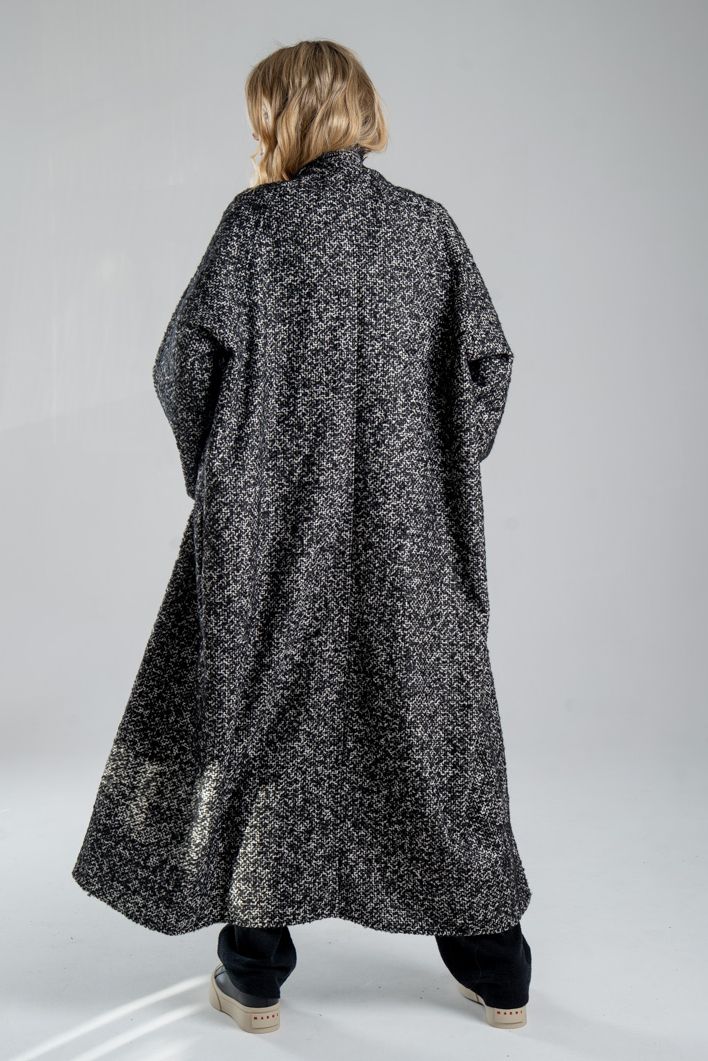 Cardigan Mino Wool delCane w czarno-białym melanżu. Modelka tyłem, w pełnej sylwetce. Wyraźnie widoczny cały tył cardiganu.
