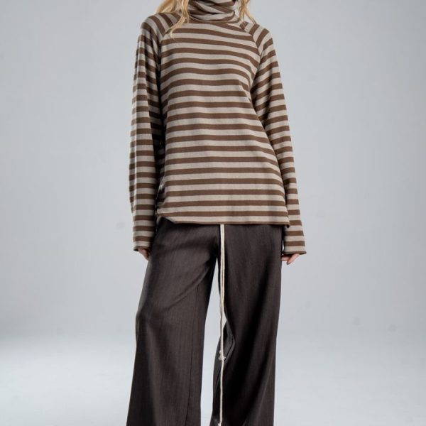 Sweter z golfem Mino Stripes delCane w beżowo-brązowe paski. Modelka w pełnej sylwetce, ustawiona przodem, z rękami swobodnie opuszczonymi wzdłuż ciała.