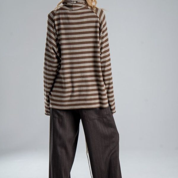 Sweter z golfem Mino Stripes delCane w beżowo-brązowe paski. Modelka w pełnej sylwetce, ustawiona tyłem, prezentuje tył swetra o luźnym fasonie oversize.