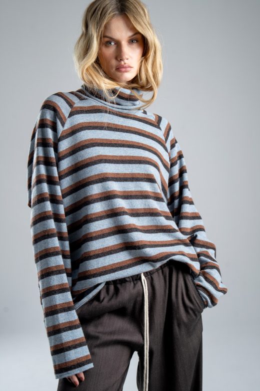 Sweter z golfem Mino Wool delCane w niebiesko-brązowe paski. Mocne zbliżenie od przodu, modelka widoczna od ud w górę. Wyraźnie widoczny golf i wzór w paski.