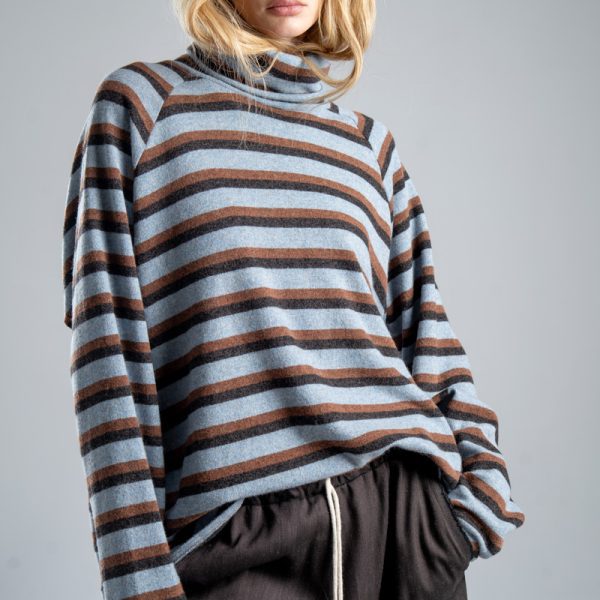 Sweter z golfem Mino Wool delCane w niebiesko-brązowe paski. Mocne zbliżenie od przodu, modelka widoczna od ud w górę. Wyraźnie widoczny golf i wzór w paski.
