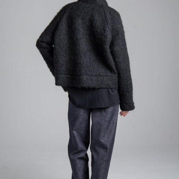 Kurtka Mino Noir delCane z czarnej wełny moherowej. Modelka w pełnej sylwetce, ustawiona tyłem, prezentuje tył kurtki o luźnym fasonie oversize.