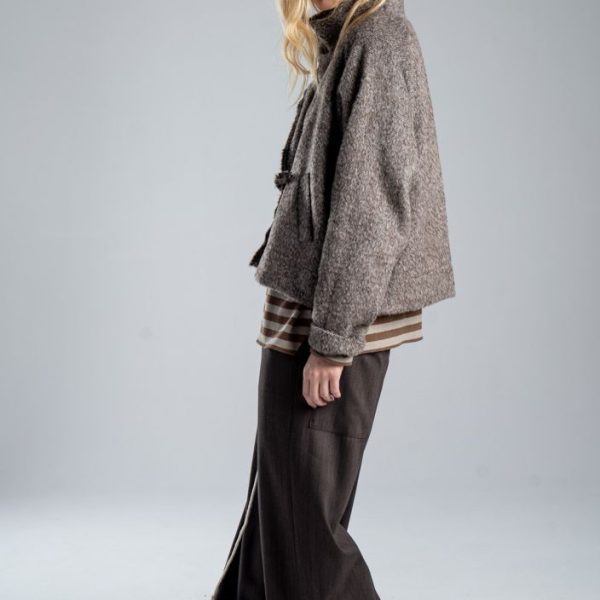 Kurtka Mino Wool delCane w melanżowy wzór w odcieniach brązu. Modelka w pełnej sylwetce, ustawiona bokiem, w rozpiętej kurtce, patrzy w obiektyw.