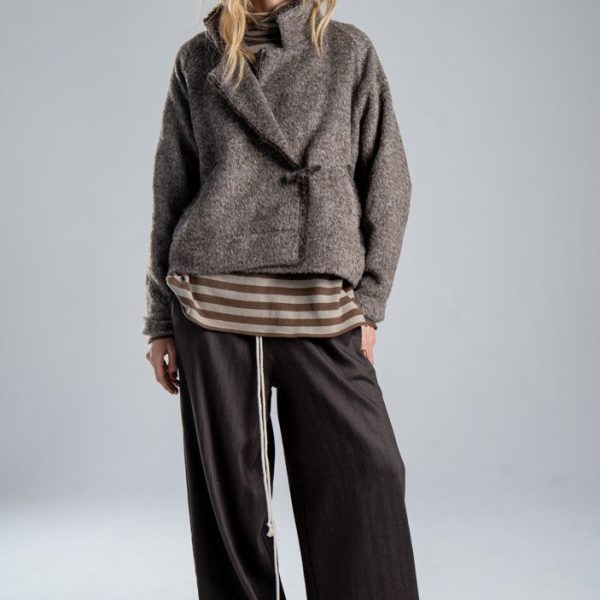Kurtka Mino Wool delCane w brązowym melanżu. Modelka w pełnej sylwetce, ustawiona przodem, prezentuje wełnianą kurtkę zapiętą na oryginalną agrafkę.