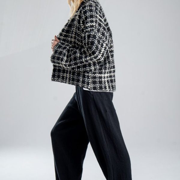 Kurtka kimono Mino Wool delCane w czarno-białym wzorze z szarymi akcentami. Modelka w pełnej sylwetce, ustawiona bokiem, z nogą wysuniętą do przodu, przytrzymuje ręką przód kurtki.