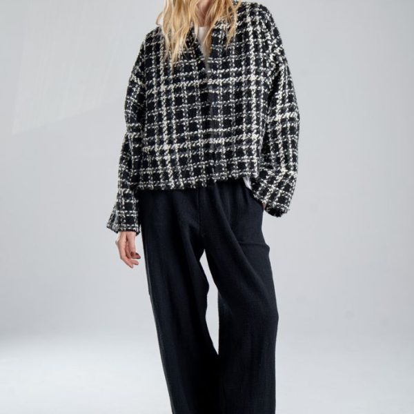 Kurtka kimono Mino Wool delCane w czarno-białym wzorze z szarymi akcentami. Modelka przodem, w pełnej sylwetce, z jedną ręką w kieszeni spodni, a drugą opuszczoną wzdłuż ciała.