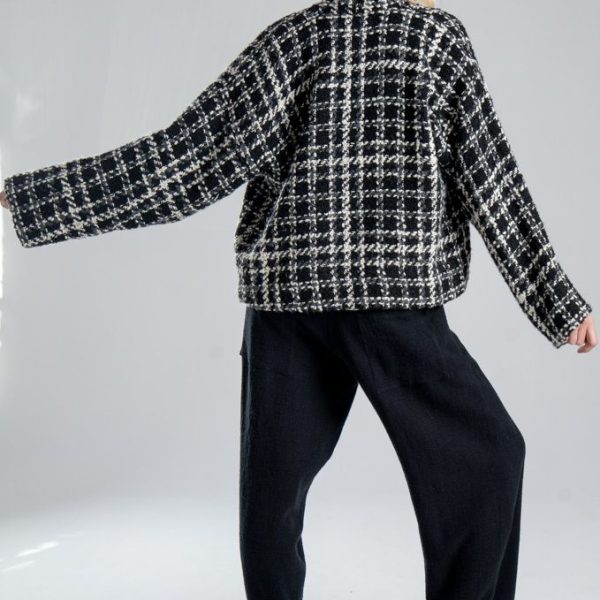Kurtka kimono Mino Wool delCane w czarno-białym wzorze z szarymi akcentami. Modelka tyłem, w pełnej sylwetce, z jedną ręką wyprostowaną w bok. Wyraźnie widoczny tył kurtki i rękaw.