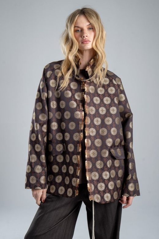Marynarka Mino Jacquard delCane z włoskiego żakardu w odcieniach zgaszonego złota i brązu. Mocne zbliżenie od przodu, modelka widoczna od ud w górę. Wyraźnie widoczny cały przód marynarki.