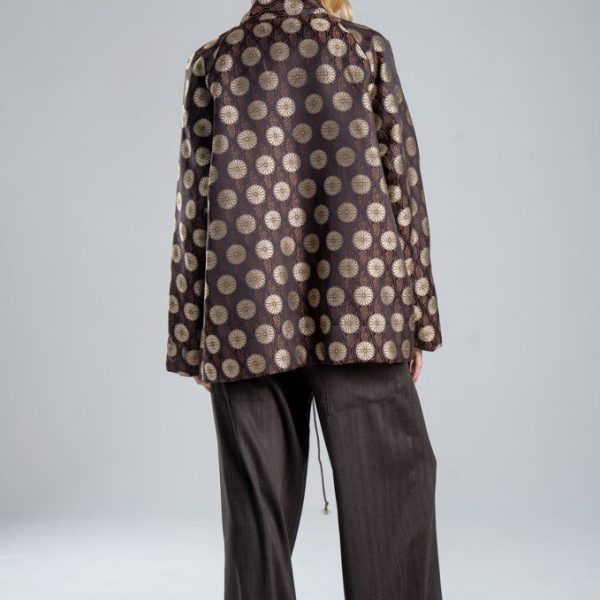 Marynarka Mino Jacquard delCane w odcieniach zgaszonego złota i brązu. Modelka w pełnej sylwetce, ustawiona tyłem, prezentuje tył marynarki o luźnym fasonie oversize.