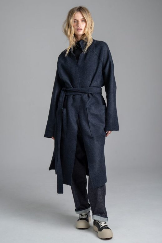 Granatowy płaszcz Mino Wool delCane, zdjęcie główne. Modelka przodem, w pełnej sylwetce, z rękami opuszczonymi wzdłuż ciała. Płaszcz zawiązany paskiem w talii.